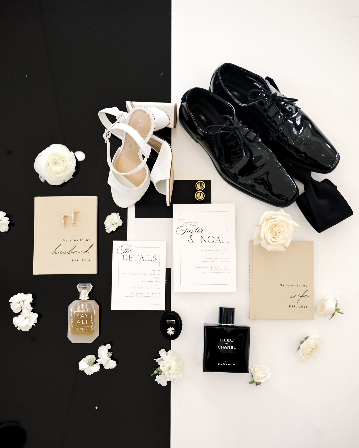 Wedding flat lay with black patent shoes, white heels, invitations, perfume, and white roses.