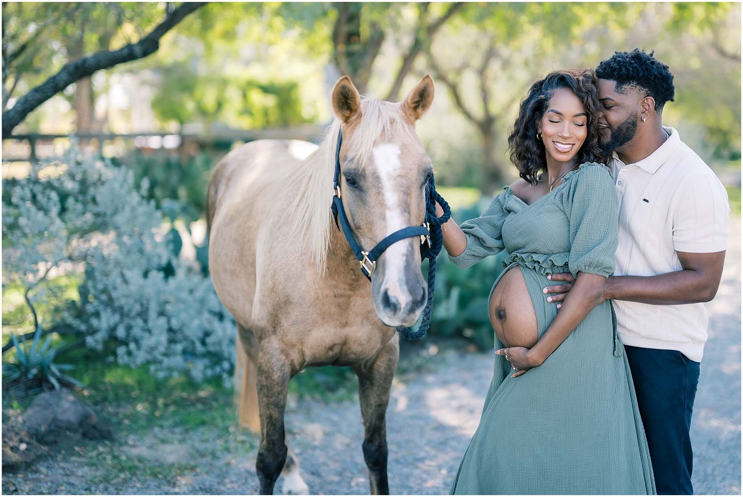 A couple laughs together during their engagement session with their horse in a sunlit outdoor setting.
