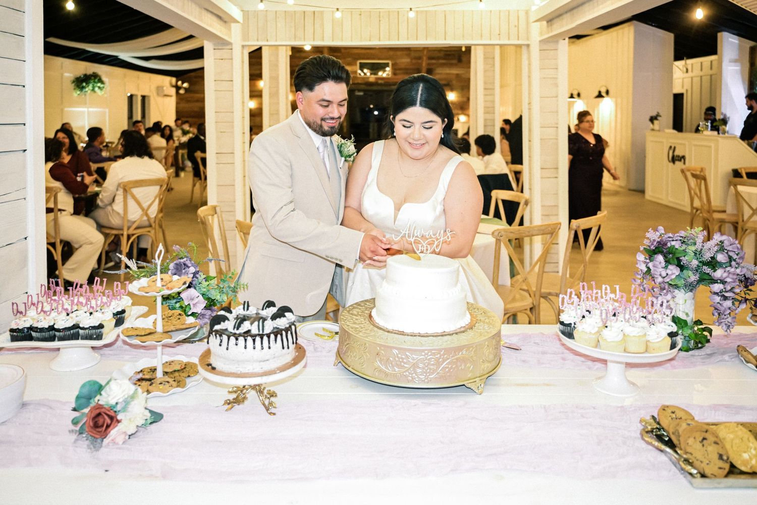 Elegant wedding reception setup with multiple desserts and cakes on display tables.