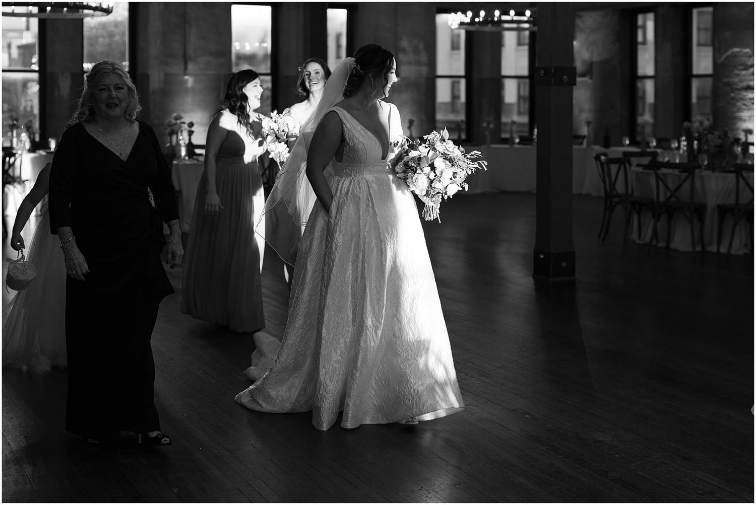 Black and white photo of dancing at an elegant indoor reception venue.