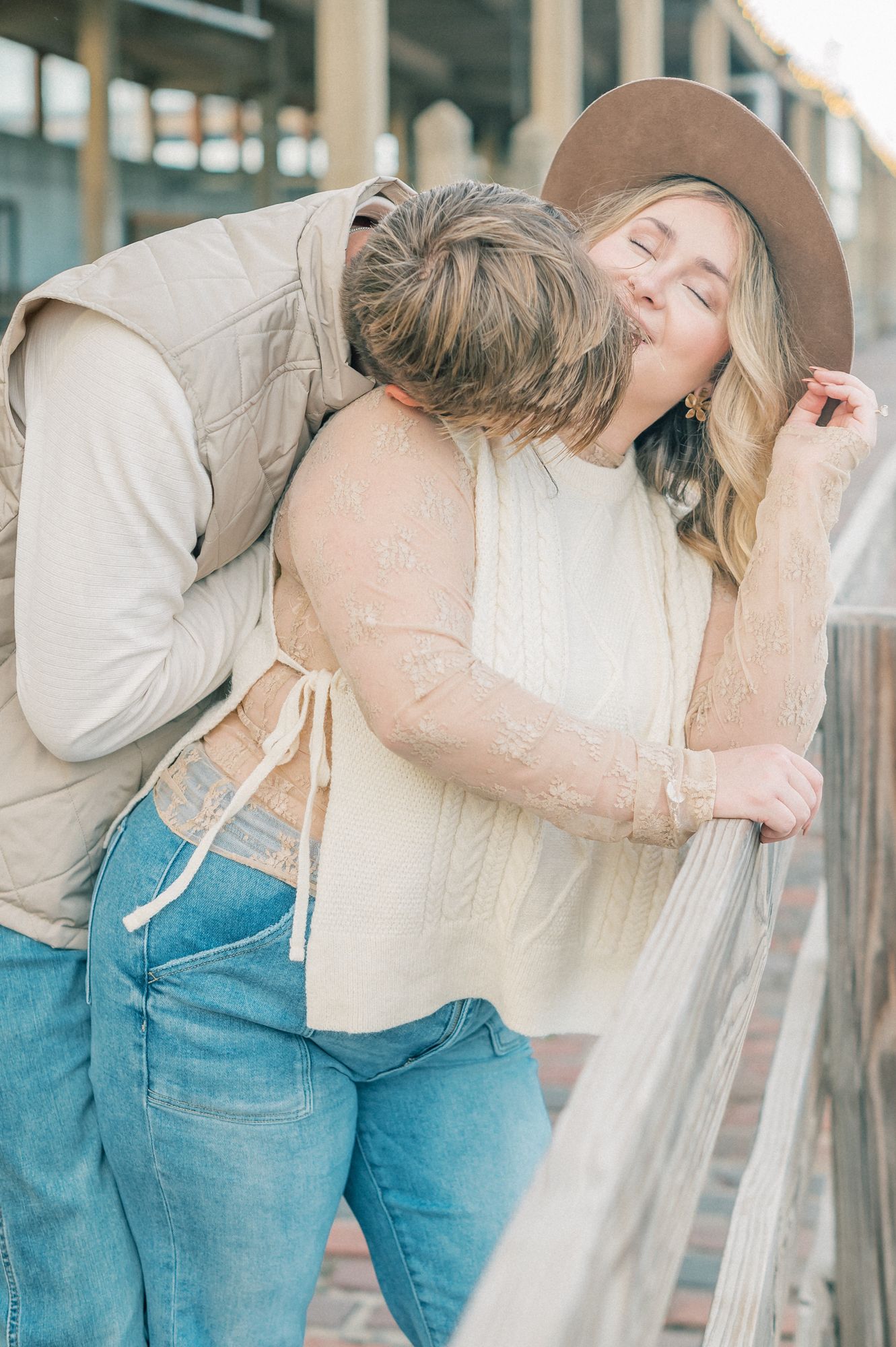 A couple sharing a tender moment in western-inspired outfits against wooden architecture.