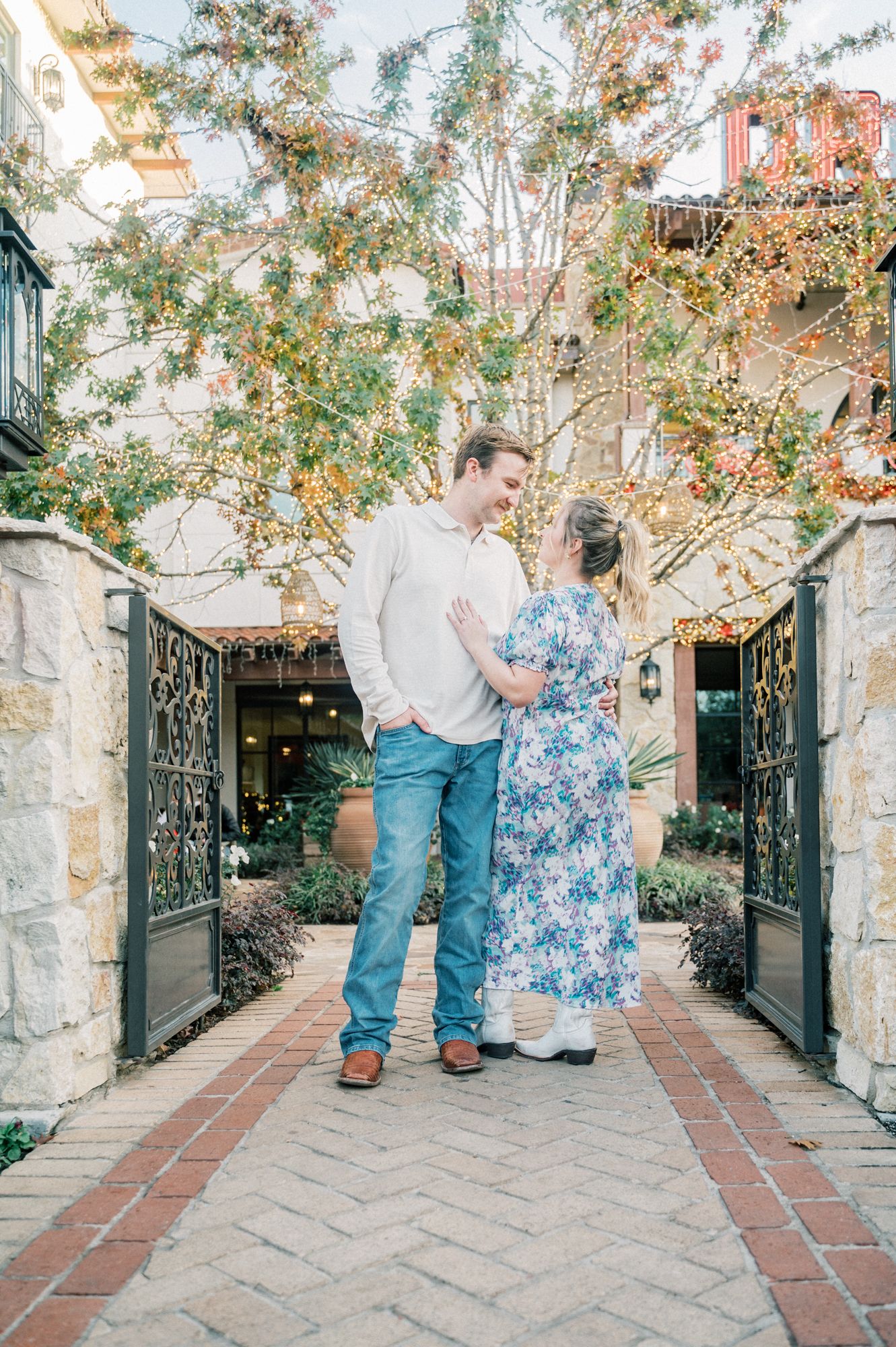 Romantic sequence along brick pathway with decorative iron gates and string lights.