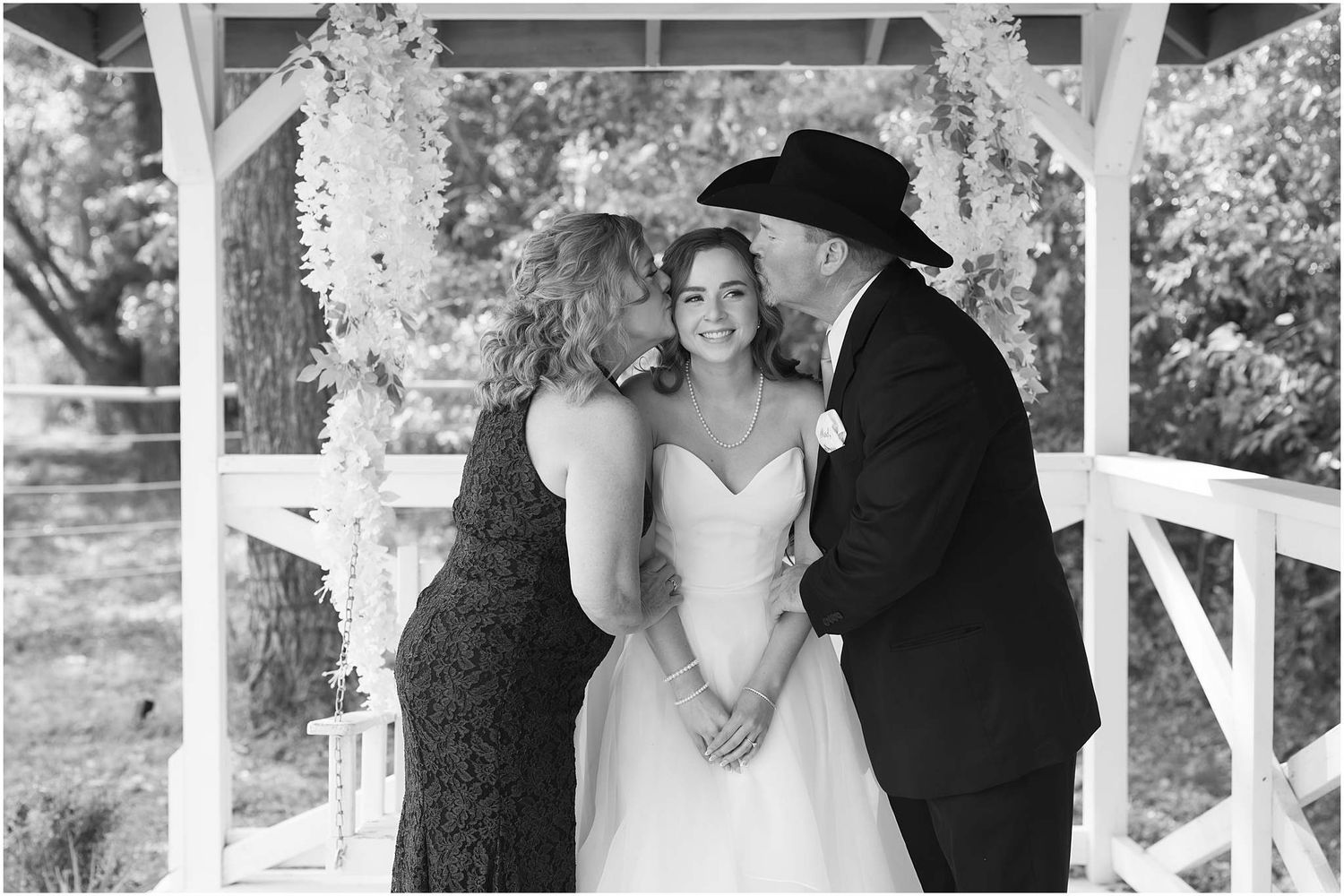 Romantic wedding couple portraits captured under a white gazebo in natural lighting.