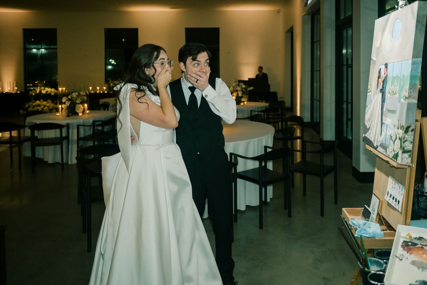 Bride and groom share an emotional moment viewing a live painting of their wedding at the reception.