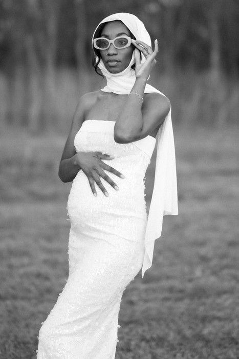 Stylish maternity shoot featuring sunglasses and white dress in black and white.