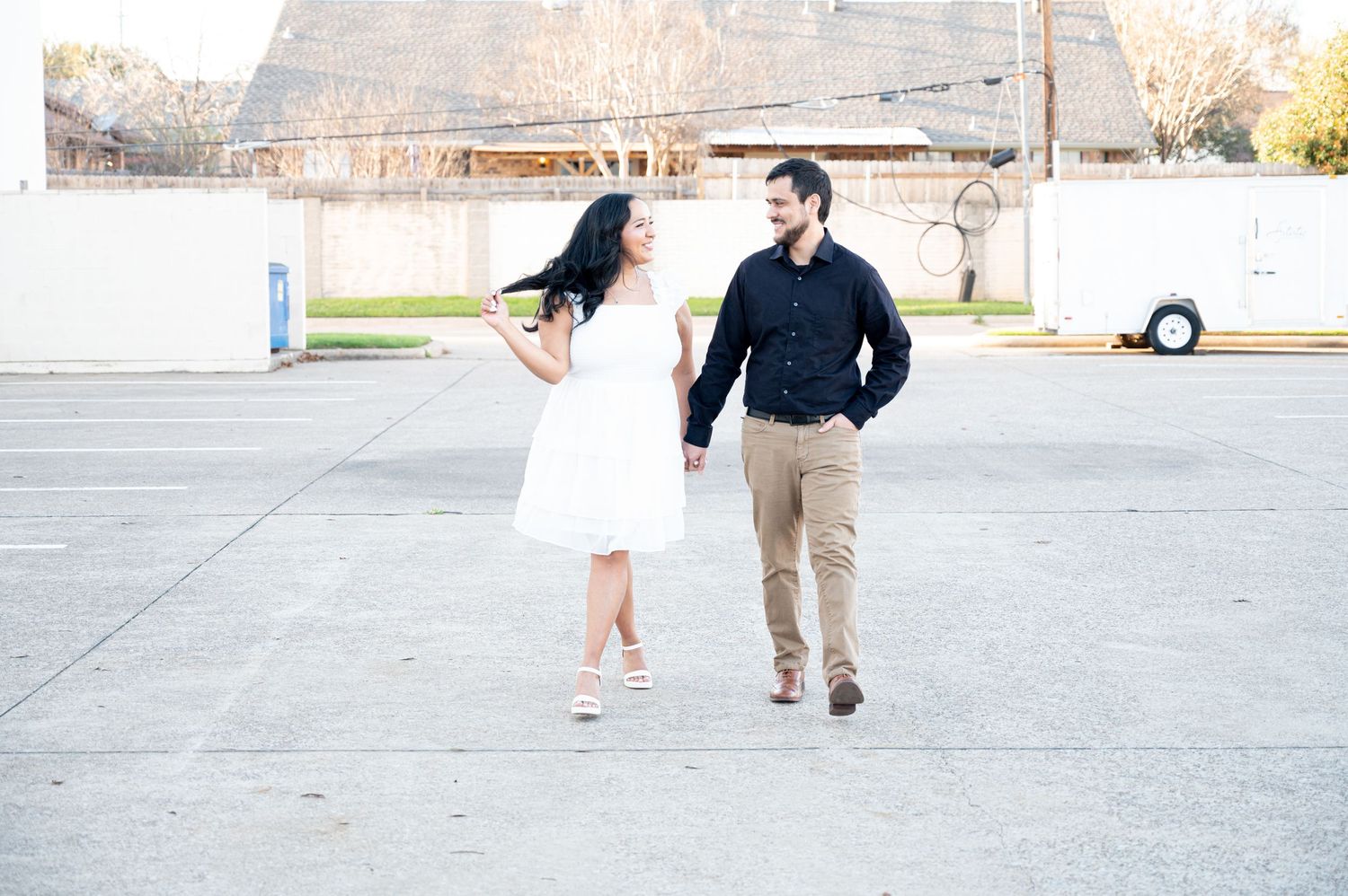 A couple playfully dancing and twirling in a casual outdoor setting.