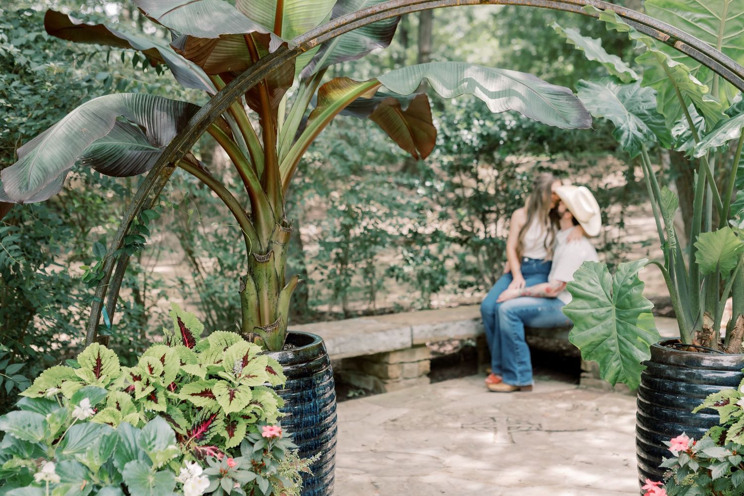 Couple sitting together on a bench in a lush tropical garden pavilion with banana trees.