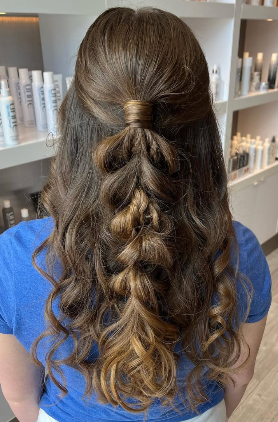 Half-up pull-through braid hairstyle with loose curls and balayage highlights, styled in a salon setting.