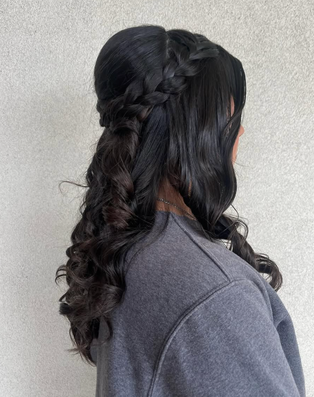 Back view of elegant half-up hairstyle with Dutch braids and long curly black hair.