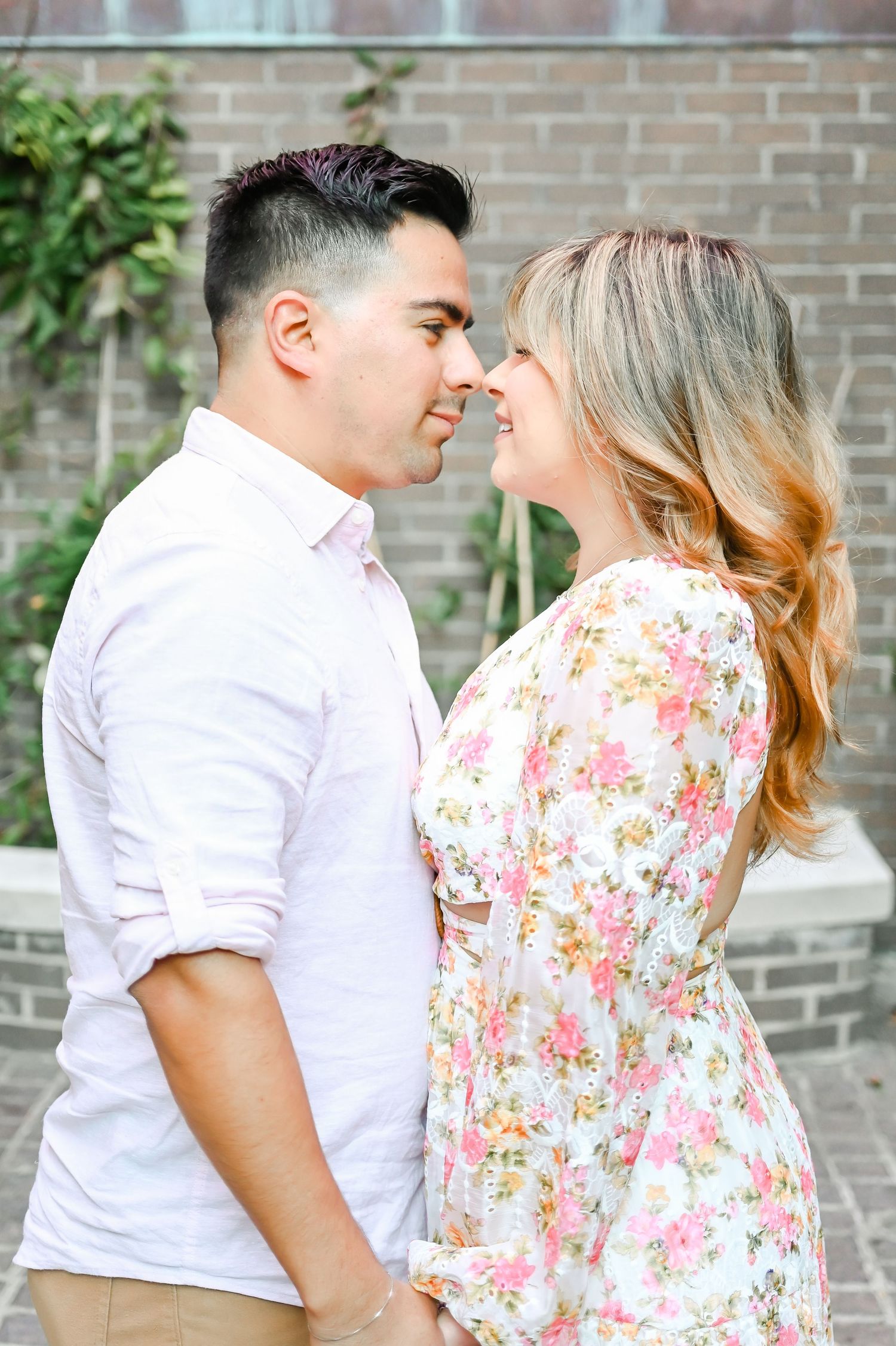 Romantic couple nearly kissing, man in white shirt and woman in floral dress.