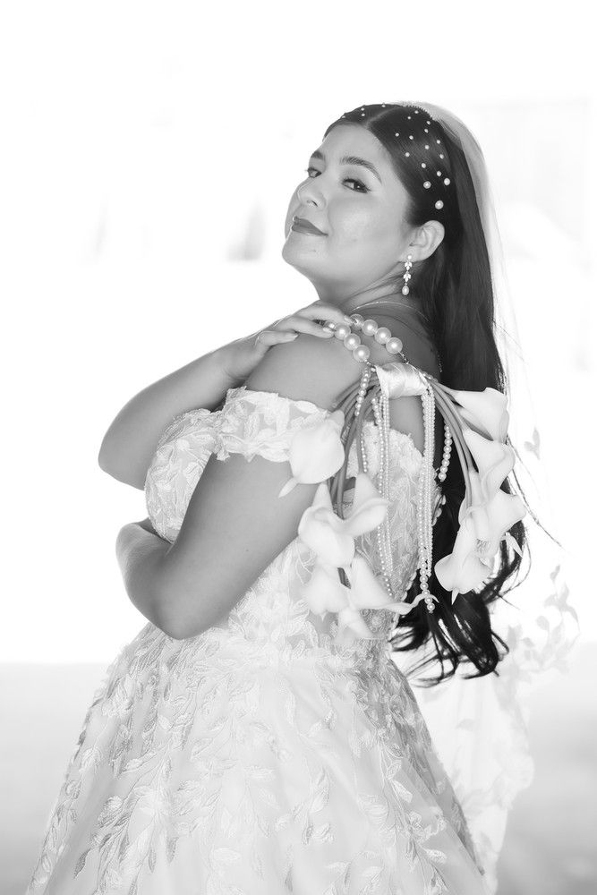 Elegant bridal portrait in black and white featuring an off-shoulder lace gown and pearl hair accessories.