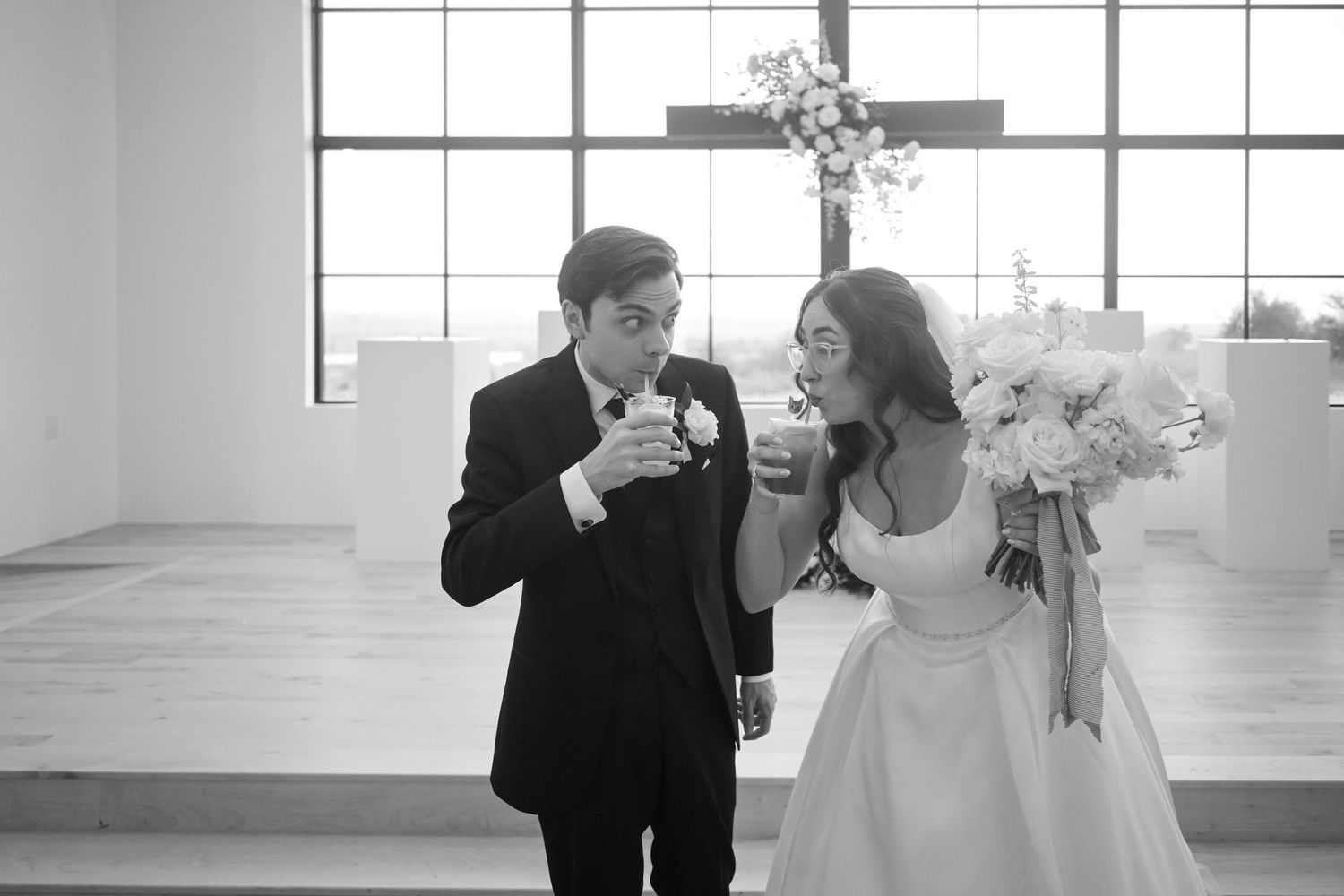 Black and white photo of bride and groom sharing a toast together after first look in chapel.