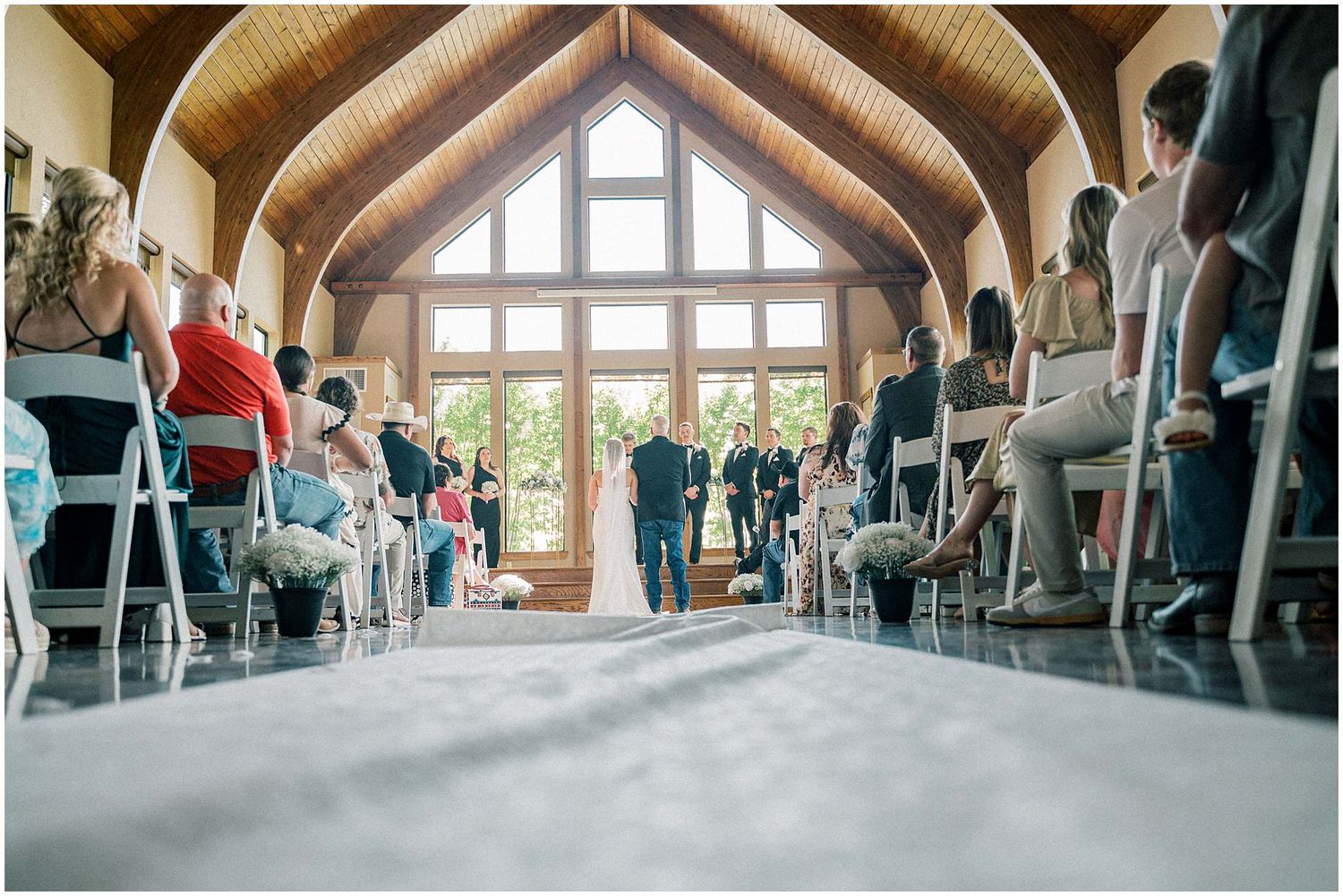 Wide view of a chapel-style wedding venue with wooden beams and guests seated.