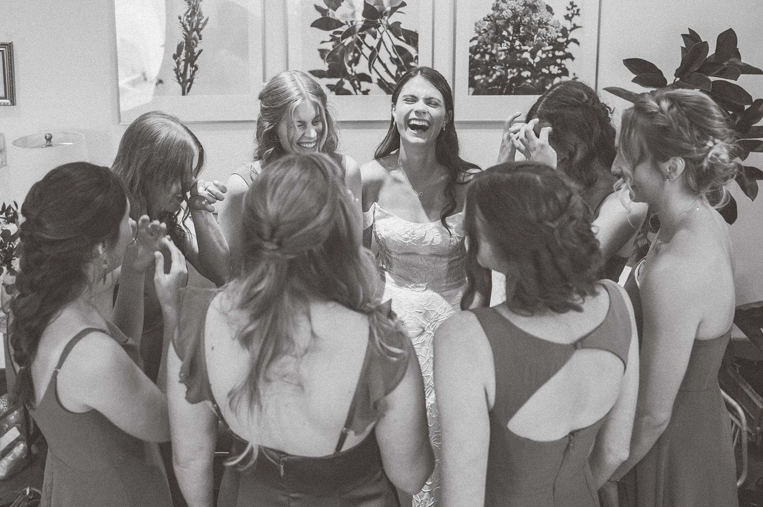 Black and white photo of bridesmaids in circle sharing pre-ceremony moment.