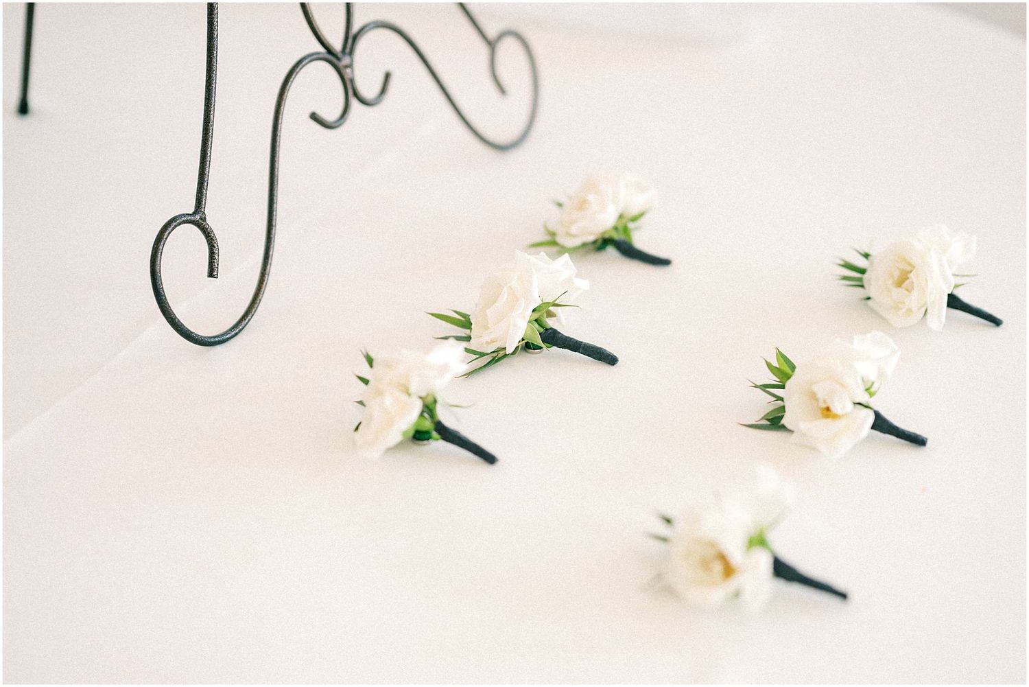 White boutonnières with elegant greenery arranged in a row.