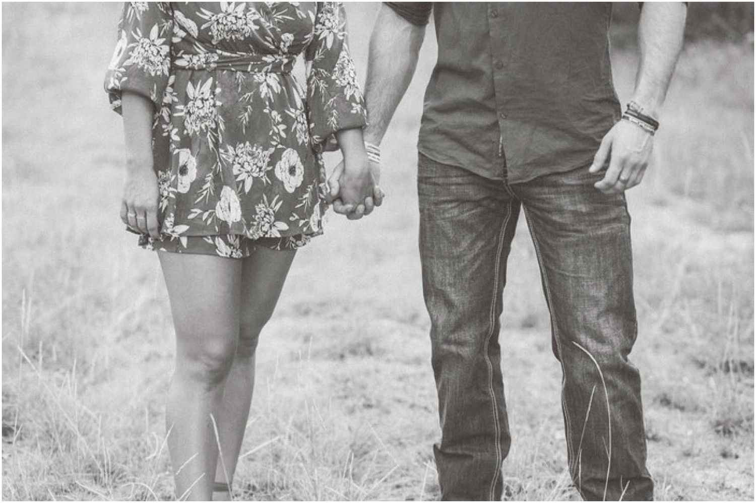 A couple stands together in a rustic outdoor setting with natural lighting.