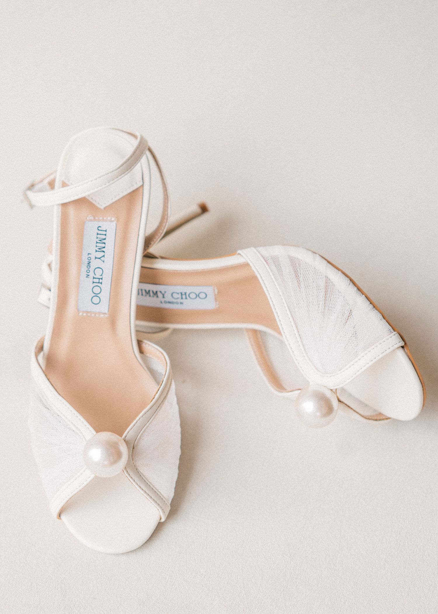 Elegant white Jimmy Choo bridal heels arranged in a row against a light background.