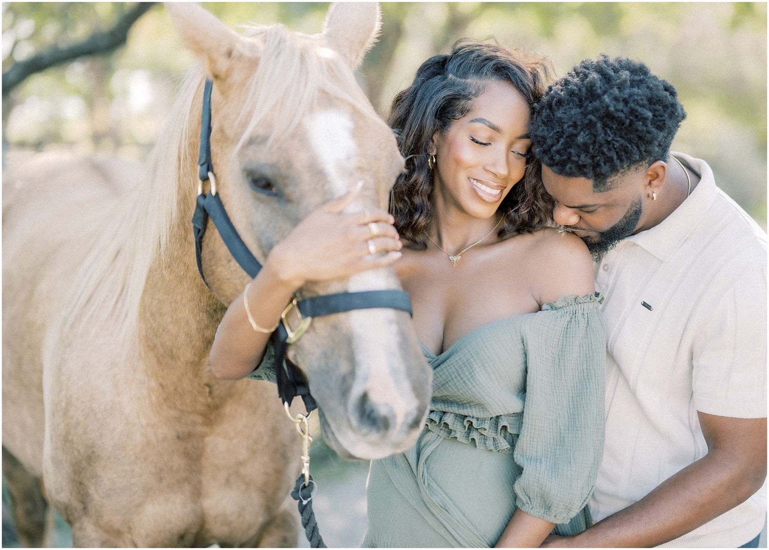 A couple poses lovingly with a light brown horse in an outdoor photoshoot.