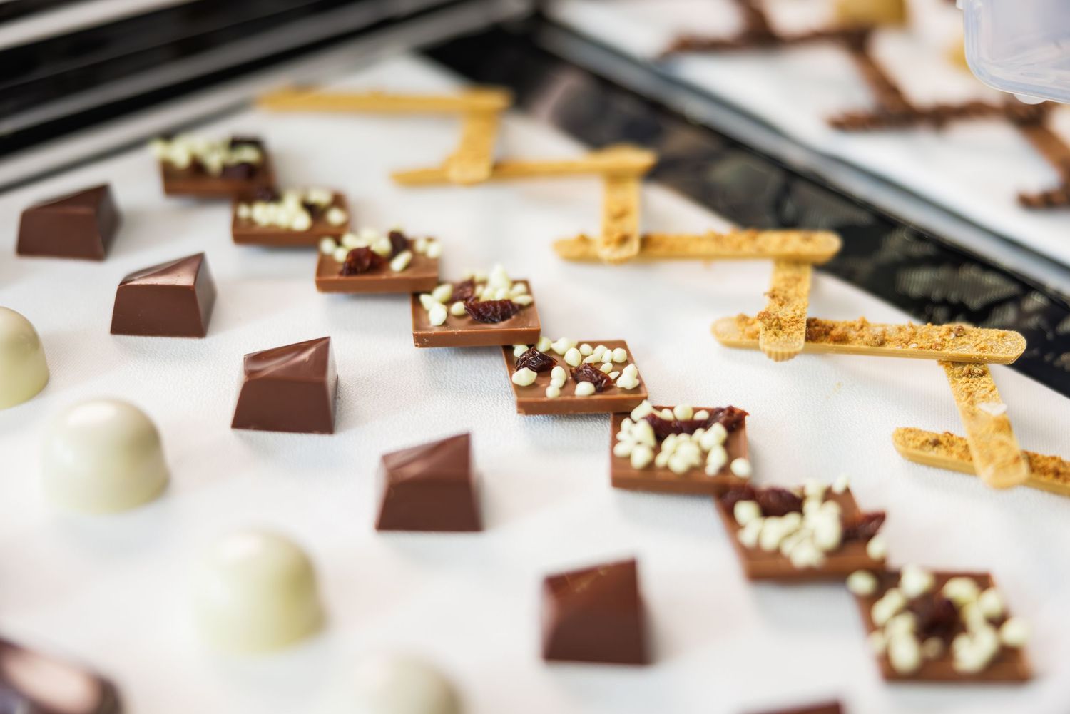 Assorted gourmet chocolates including dark, milk, and white chocolate squares and truffles displayed on a white surface.