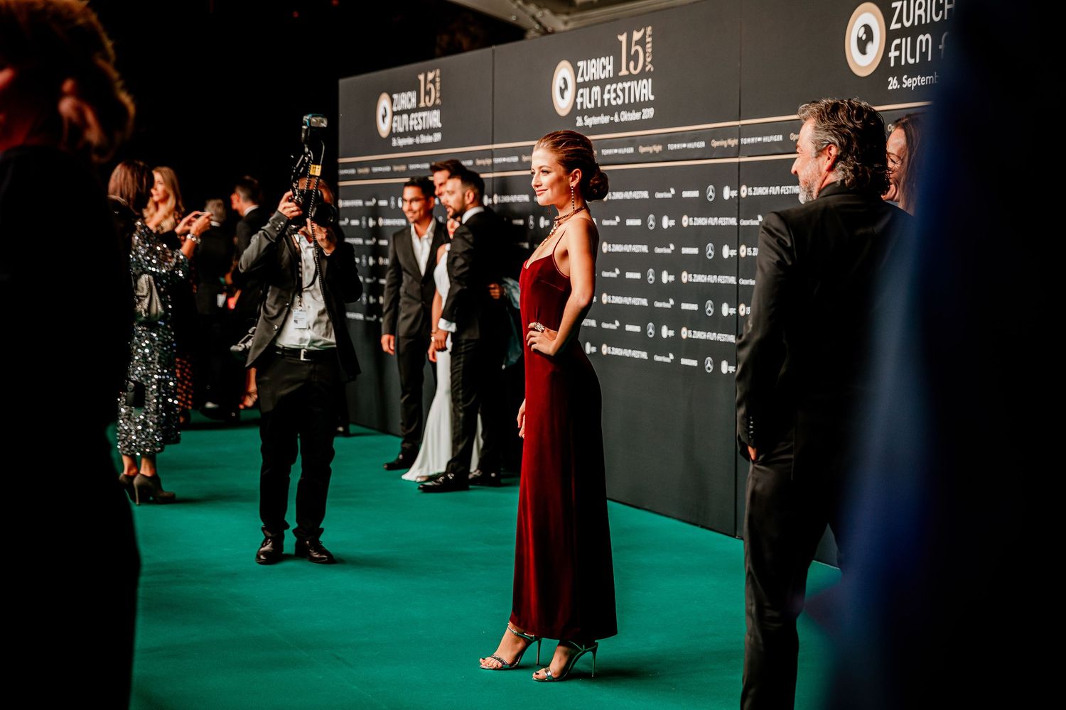 Celebrities pose on green carpet at Zurich Film Festival 15th edition, with photographers capturing glamorous evening looks.