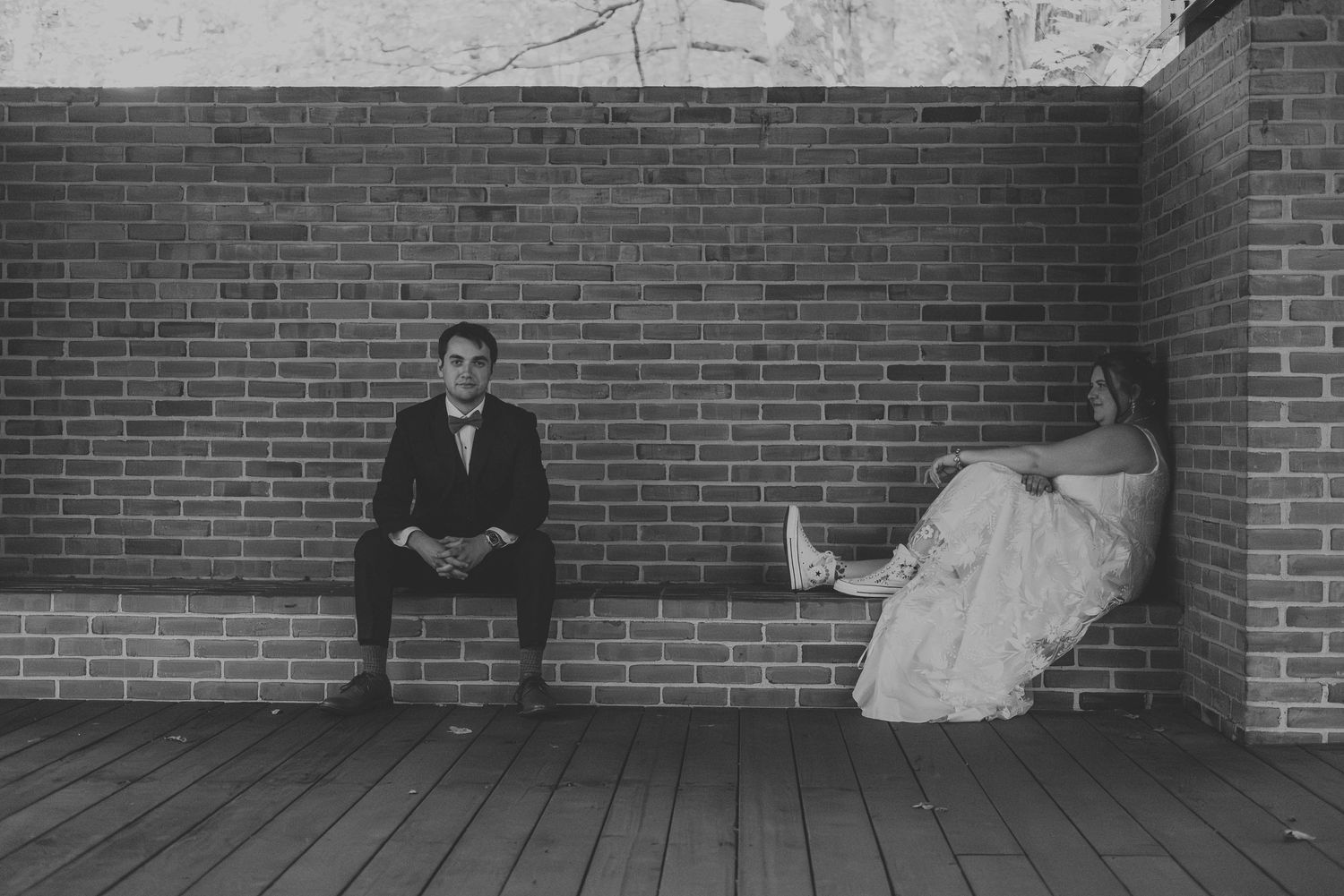 Black and white photo series showing a couple seated against a brick wall with dramatic shadows.