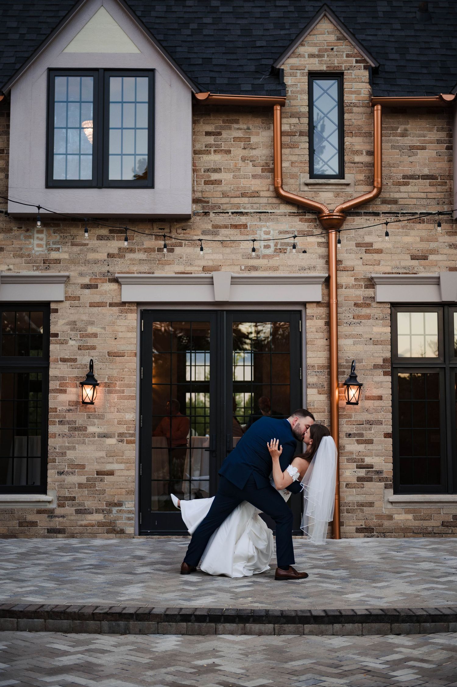 Artistic sequence of wedding portraits against stone building exterior with copper lanterns.