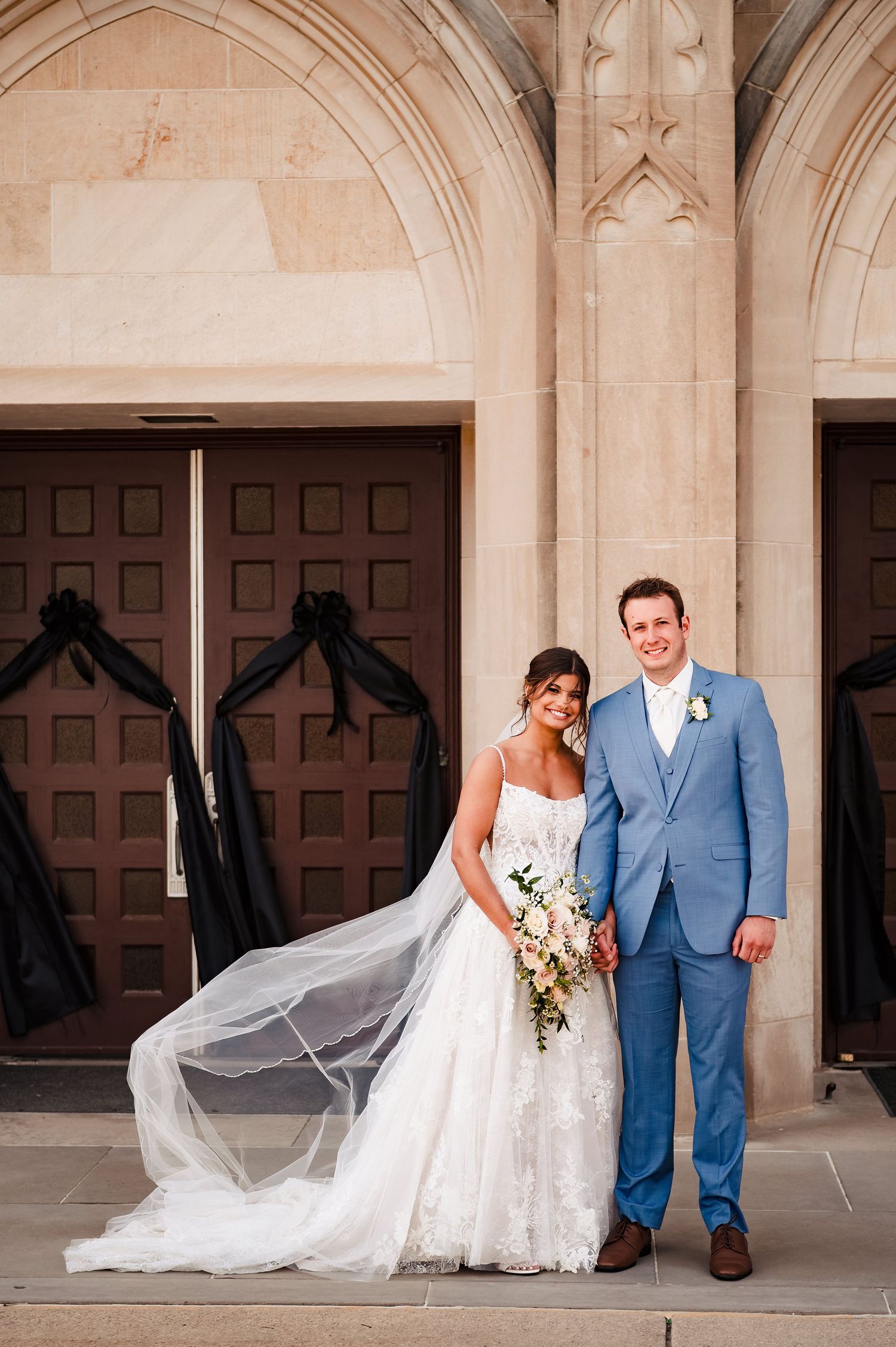 A wedding couple poses in front of ornate stone archways and wooden doors in a series of romantic portraits.