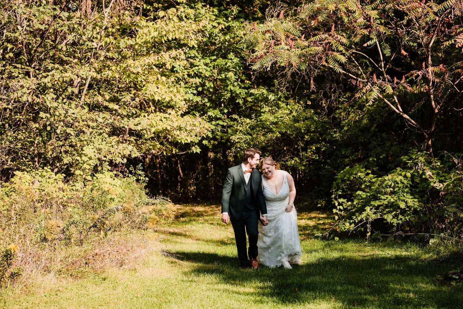 A couple shares a tender moment in a sunlit garden setting during their wedding day.
