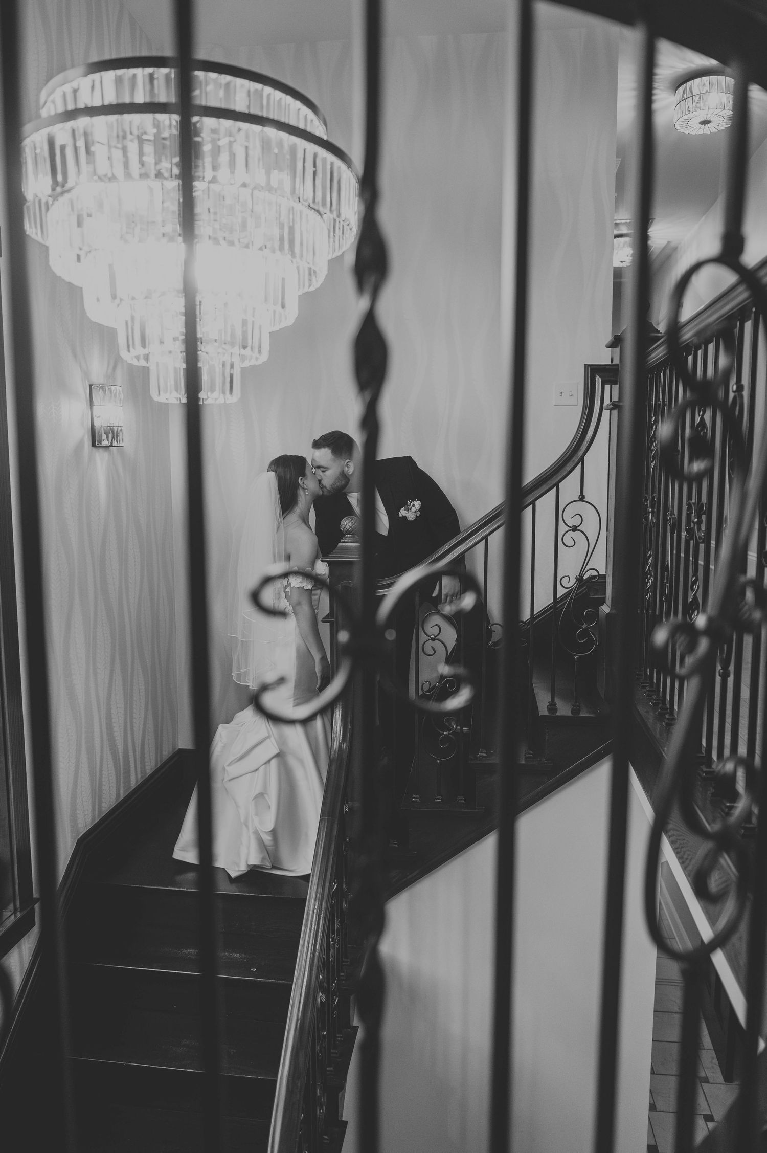 Dramatic black and white staircase sequence with chandelier and architectural details.