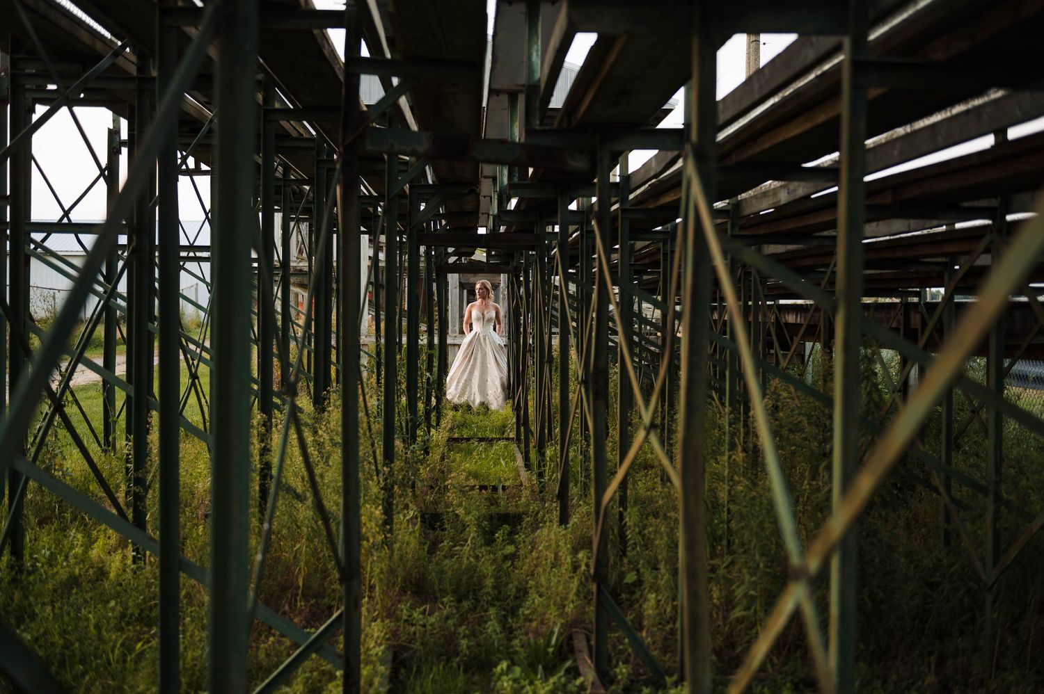 Wedding couple silhouetted among industrial metal beams and natural greenery.