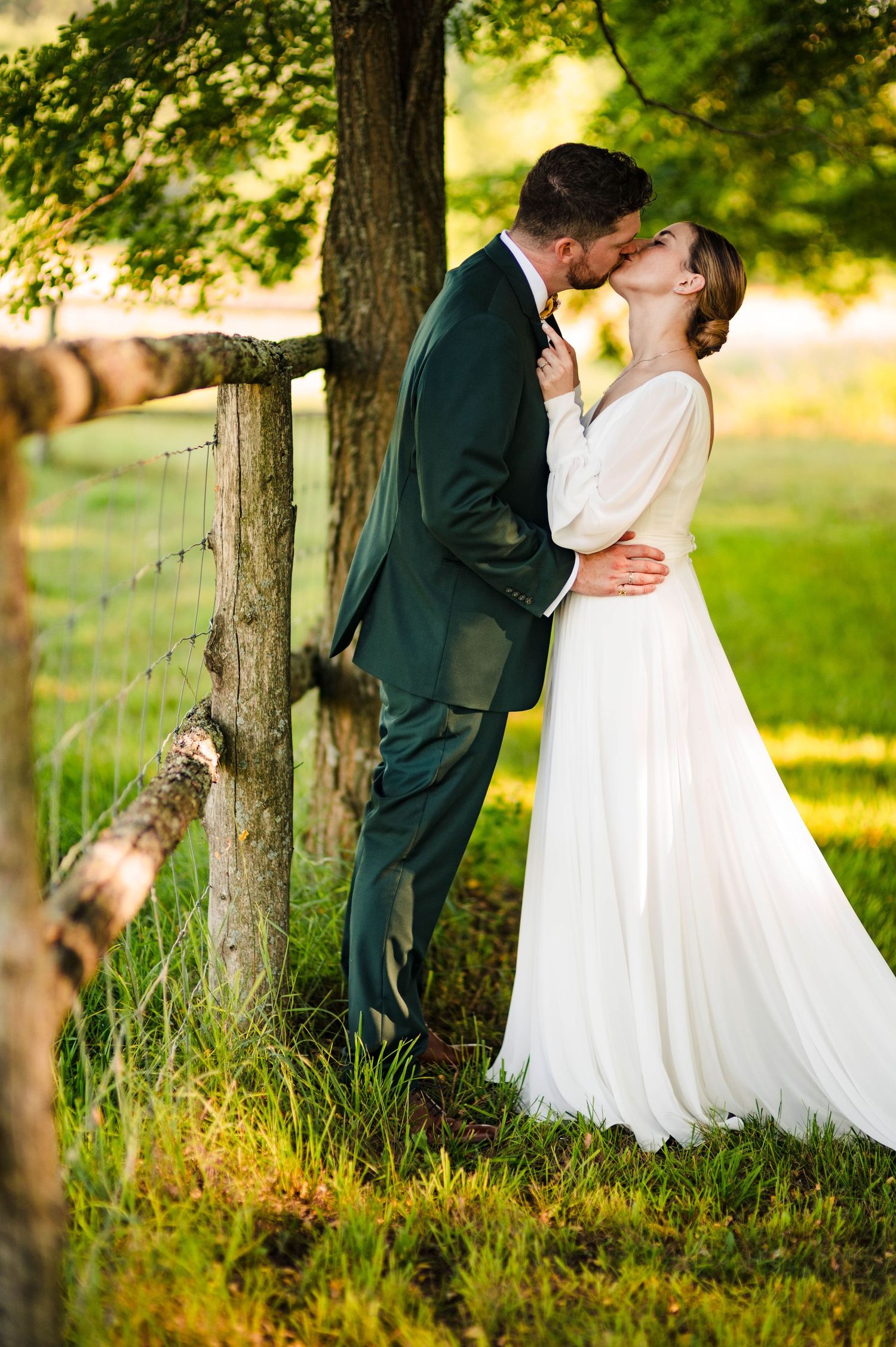 Wedding couple shares romantic moments among trees in golden evening light.