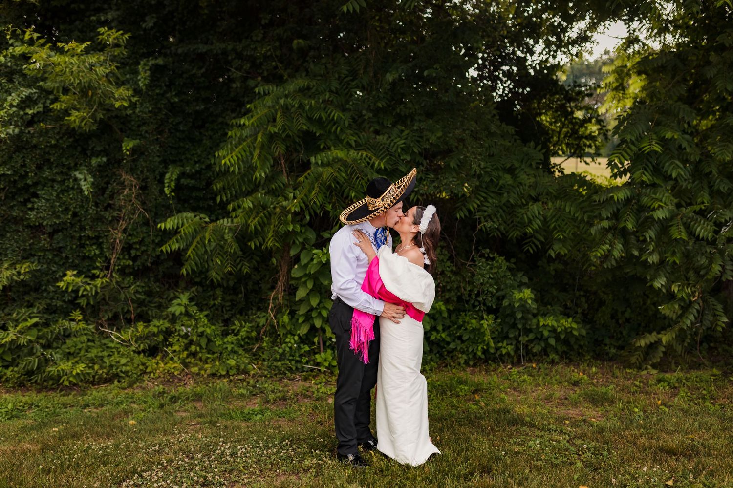 A couple embraces during a romantic outdoor photo session in a lush green garden setting.