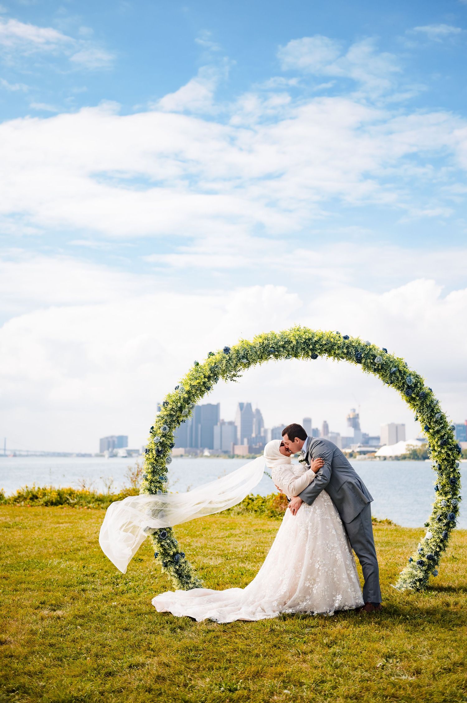 A couple shares a romantic moment under a floral arch with a city skyline in the background across multiple frames.