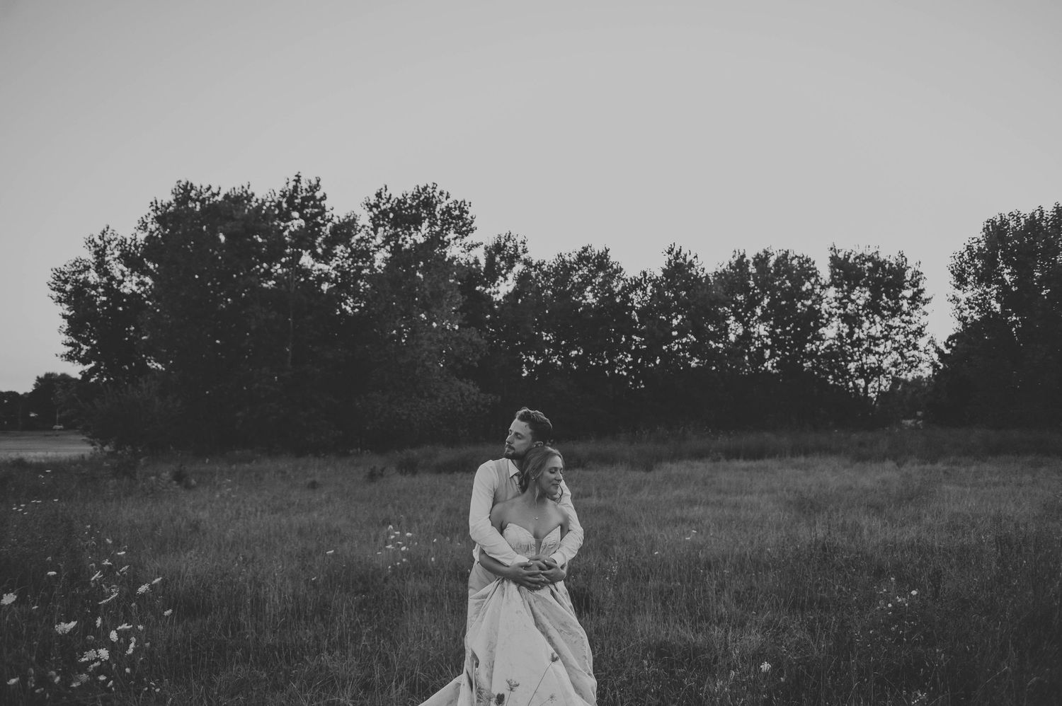Minimalist black and white wedding portraits in an open field landscape.