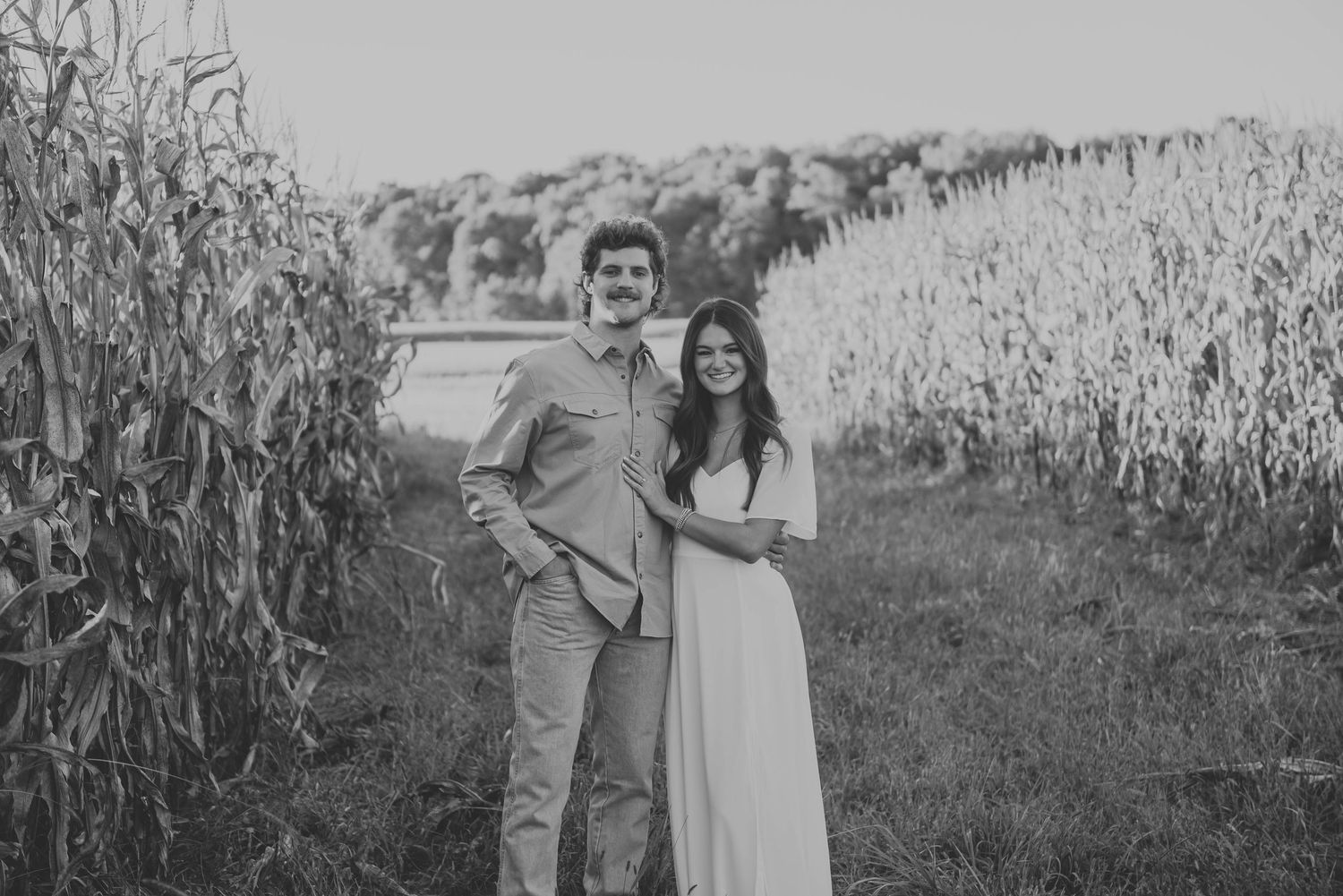 Black and white portrait of couple in rustic farm setting.