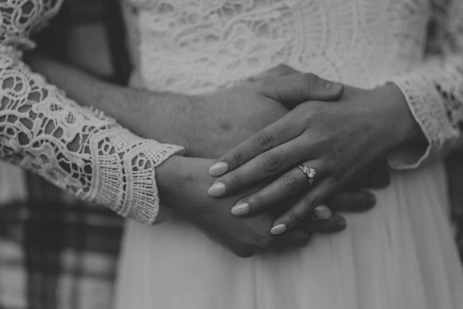 Close up of hands holding in white lace dress detail.