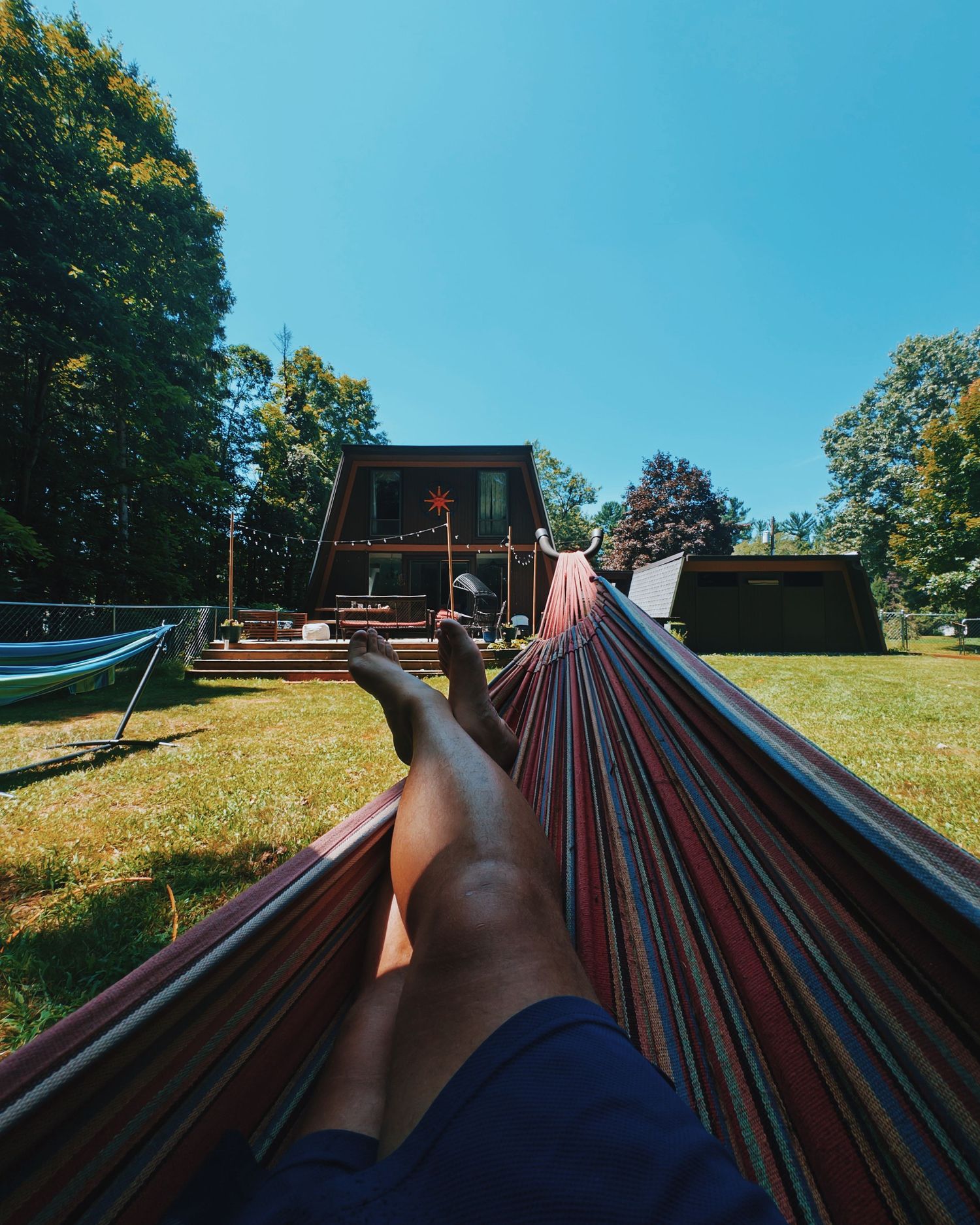 Relaxing view from a colorful striped hammock on a sunny summer day.
