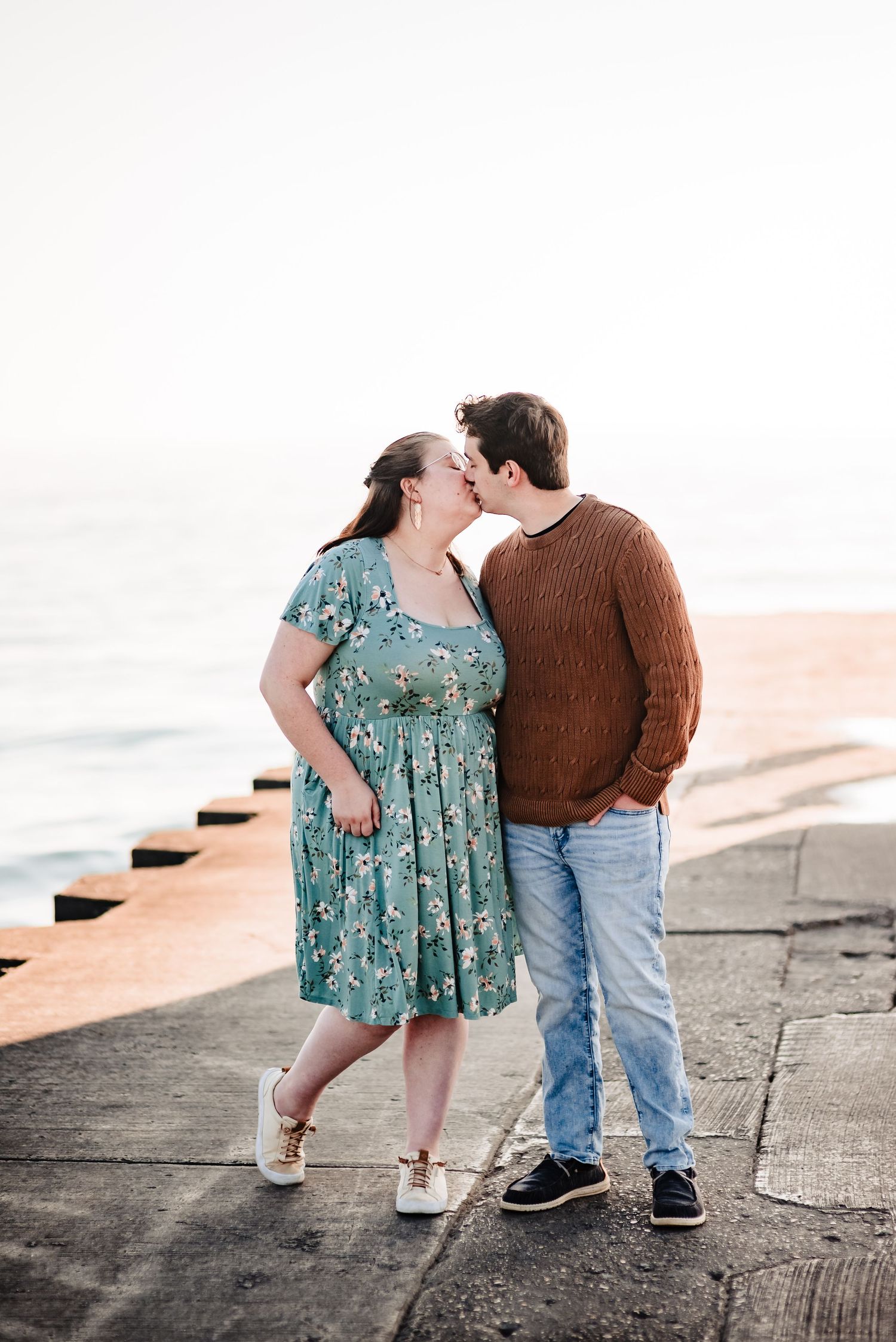 A romantic moment shared between a couple on a seaside walkway.