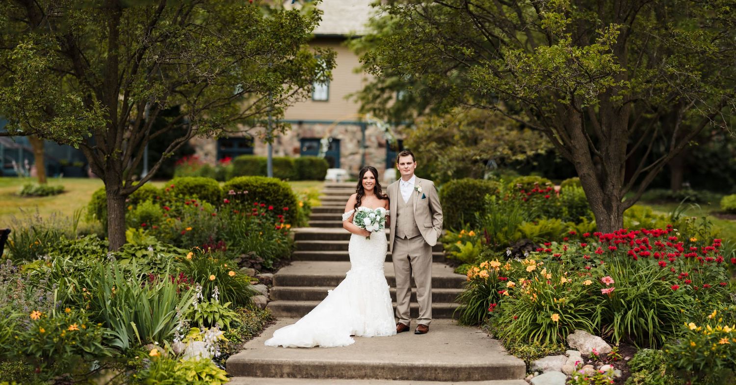 A scenic garden walkway with stone steps leads through colorful yellow and red flowers in a landscaped setting.