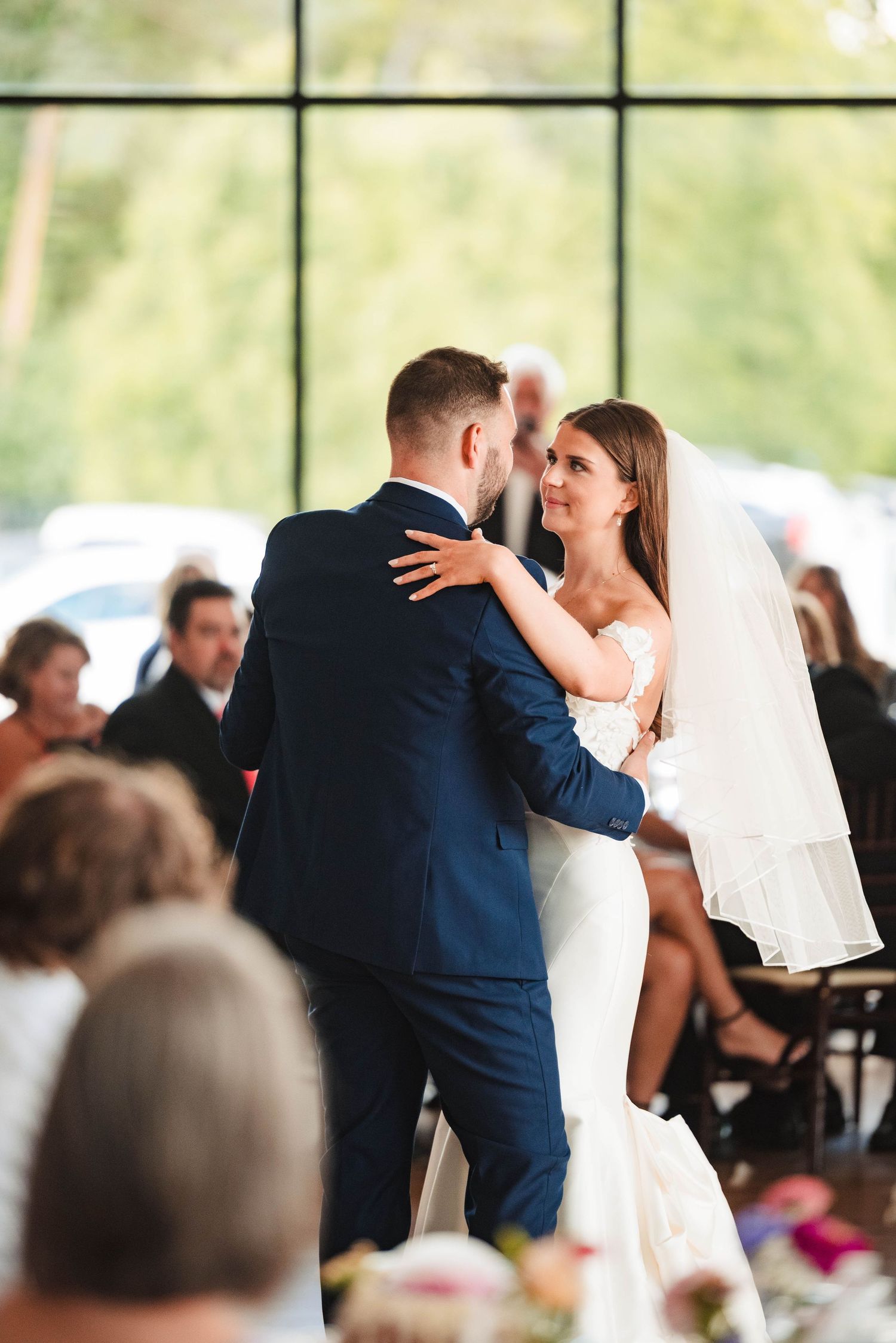 Newlyweds share their first dance at an indoor wedding reception venue.
