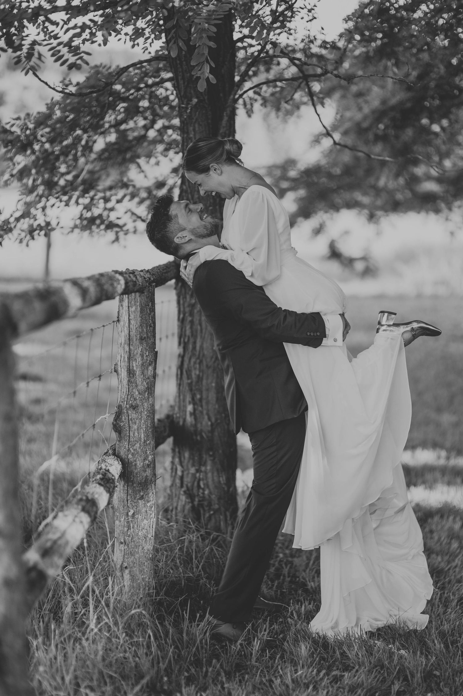 Black and white sequence of a couple dancing playfully by a rustic fence.