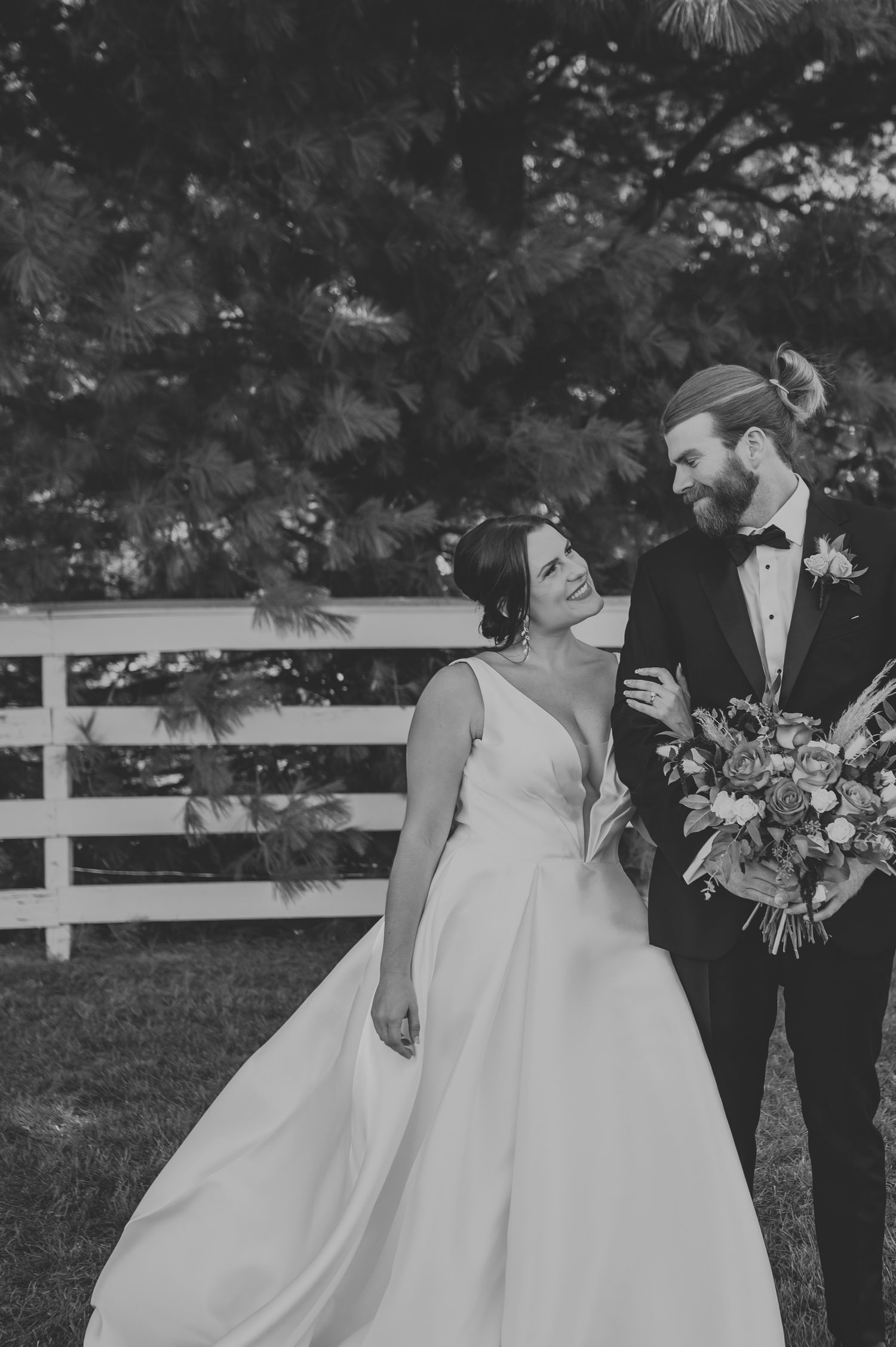 Black and white wedding photo series showing romantic moments between a bride in a ballgown and groom in a tuxedo outdoors.