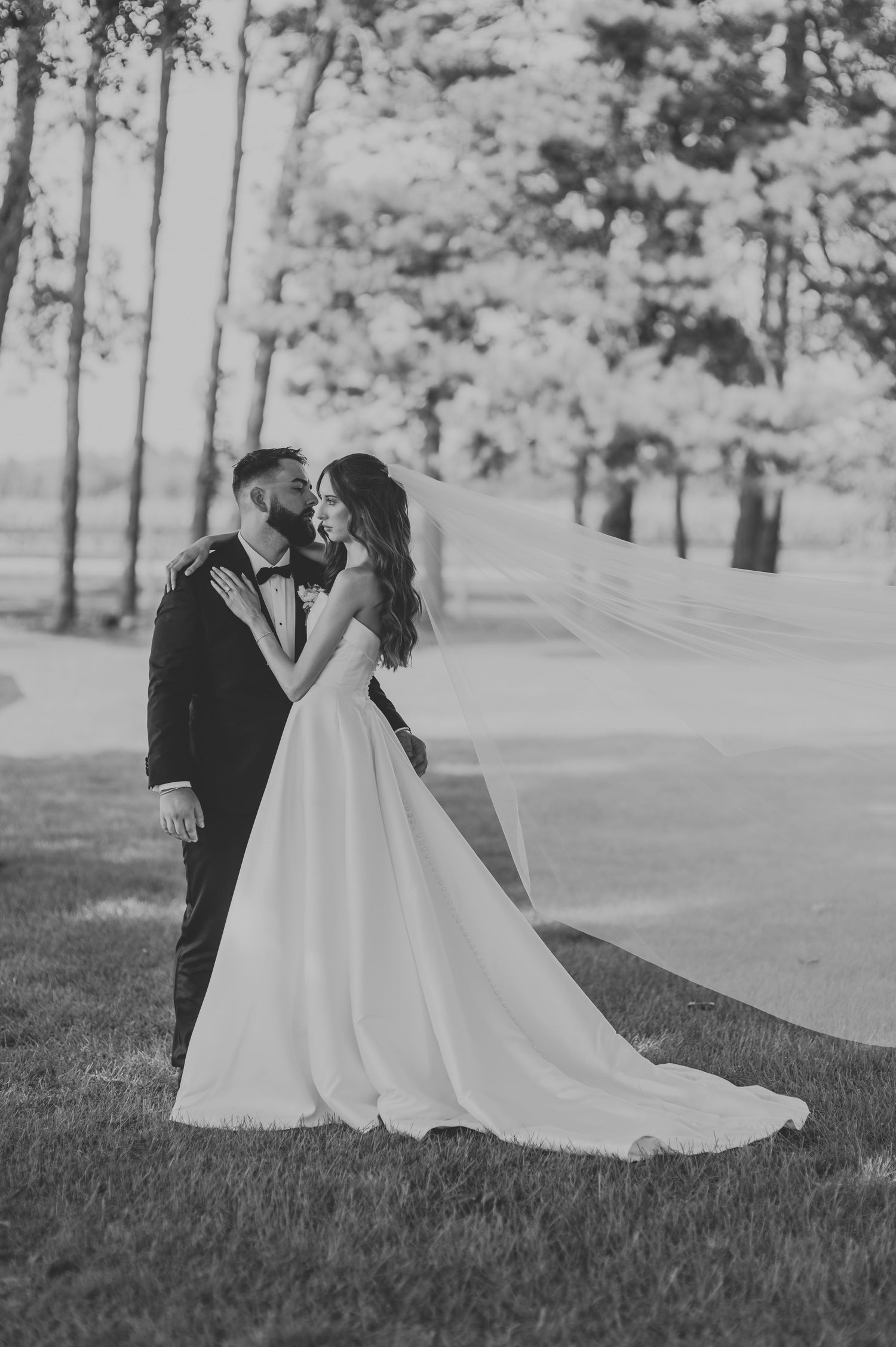 A romantic wedding couple embraces on a grassy hillside in a series of black and white photos.