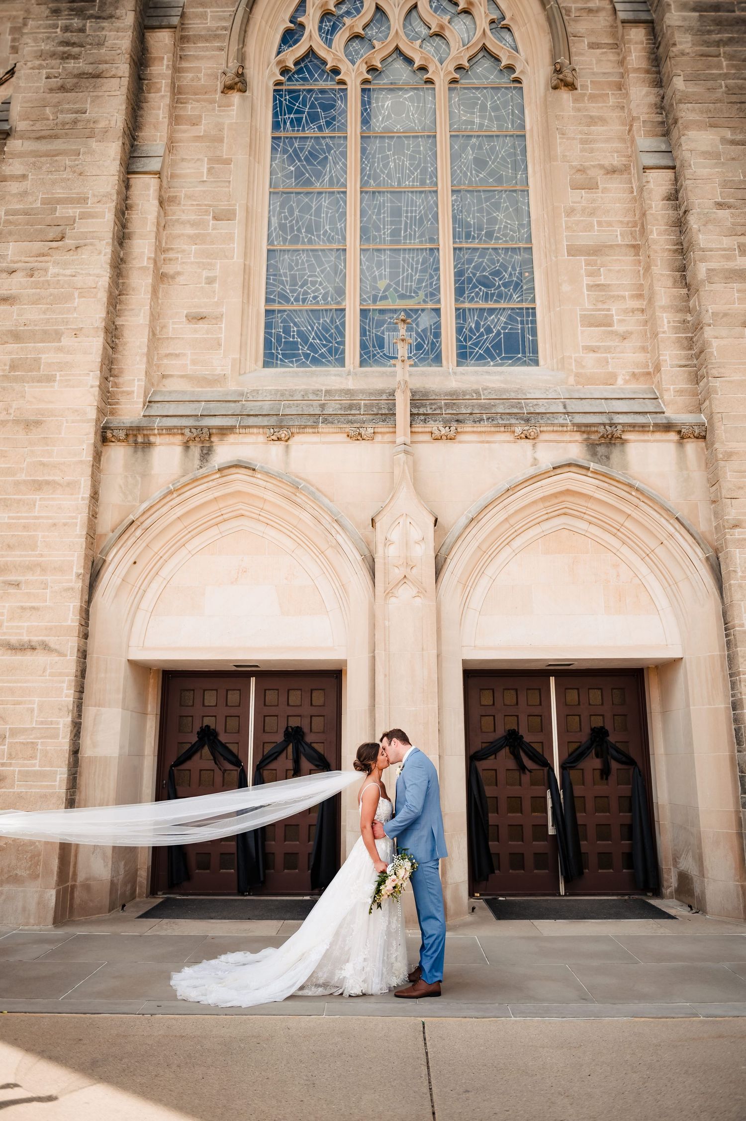Gothic church entrance with flowing veil and romantic moment.