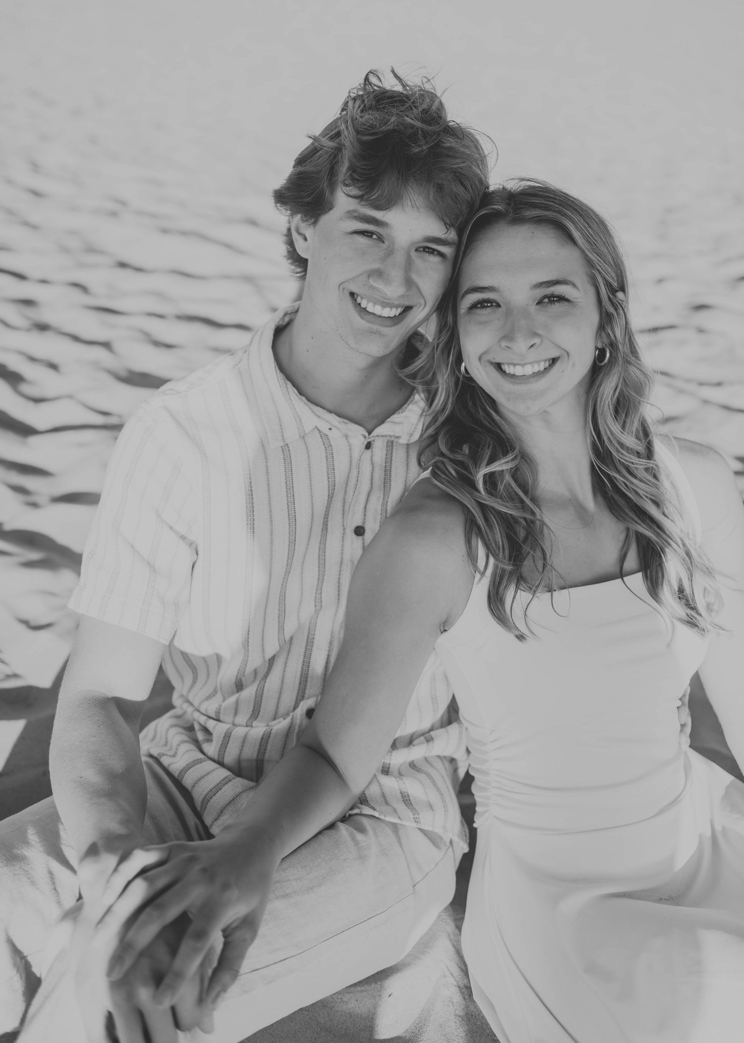 Black and white beach portrait of couple in casual summer attire.