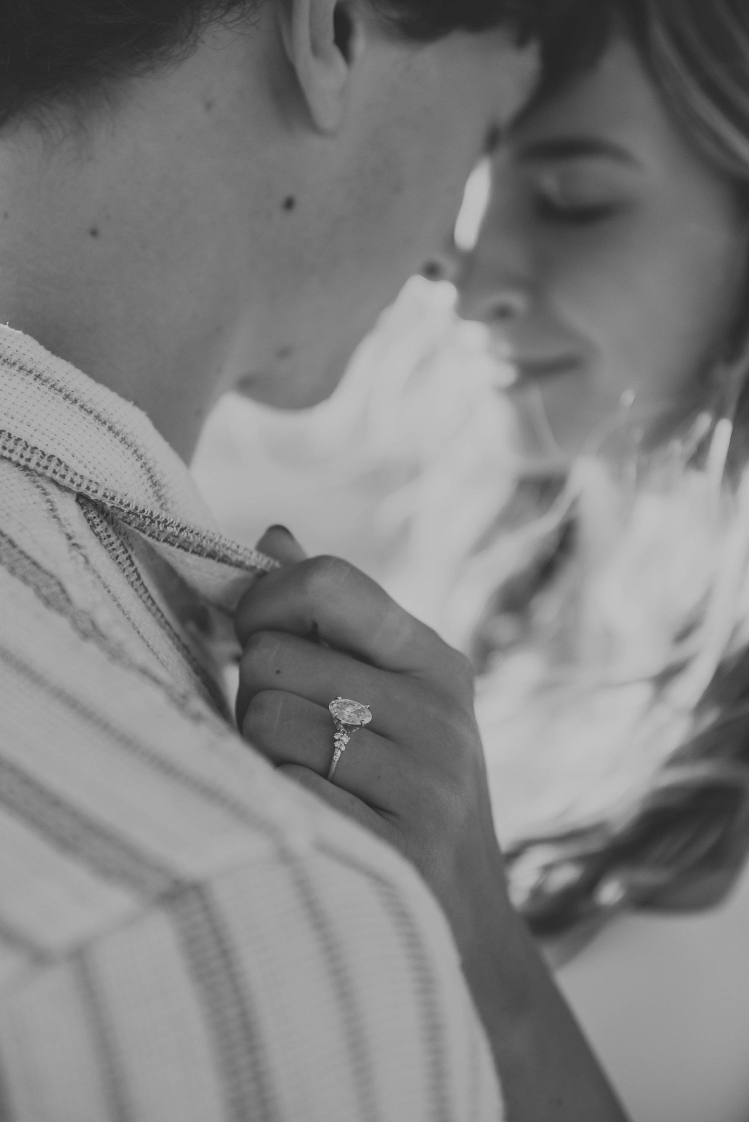 Close-up black and white photo showcasing engagement ring during intimate moment.
