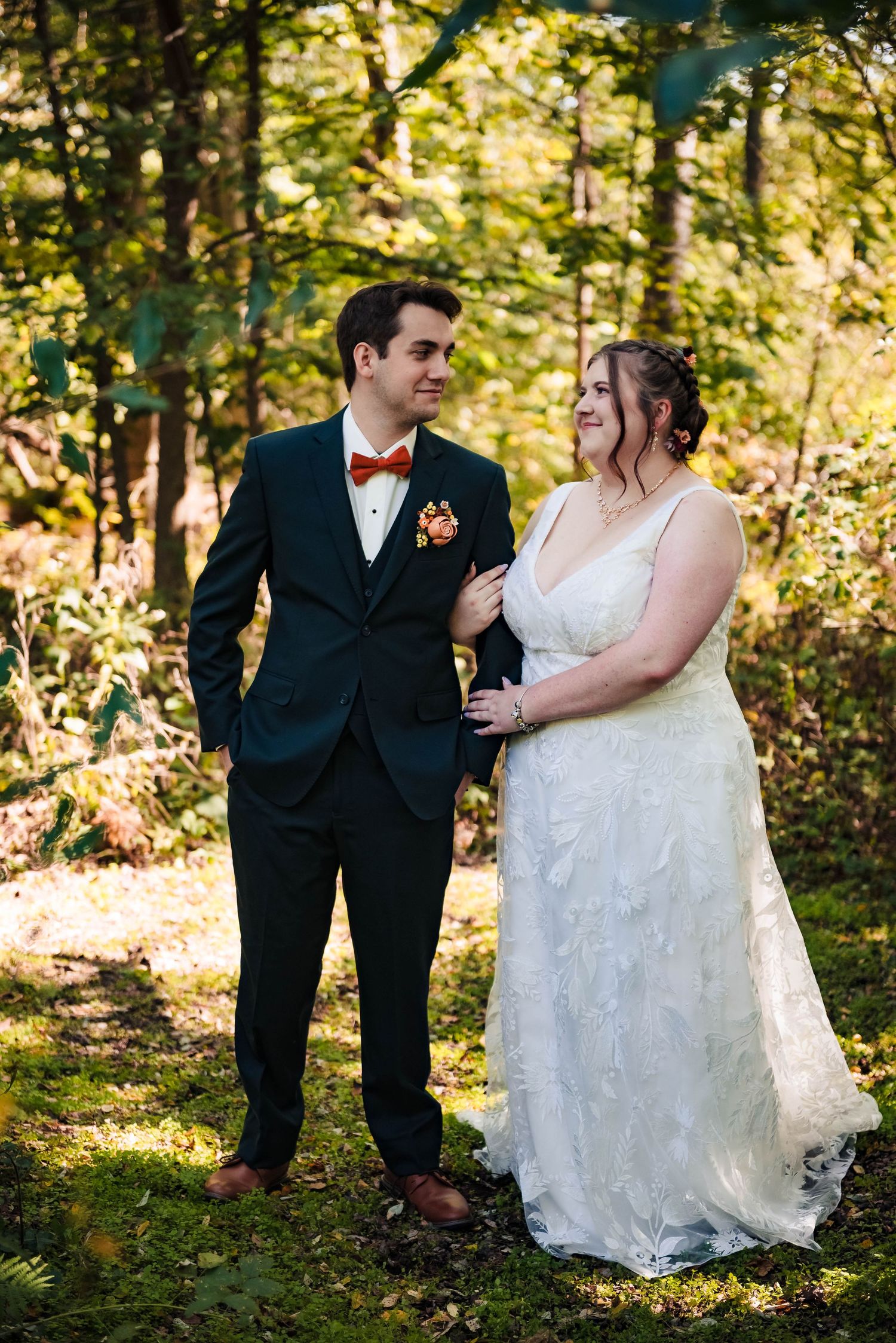 A couple shares a lighthearted moment together in a forest setting during their wedding.