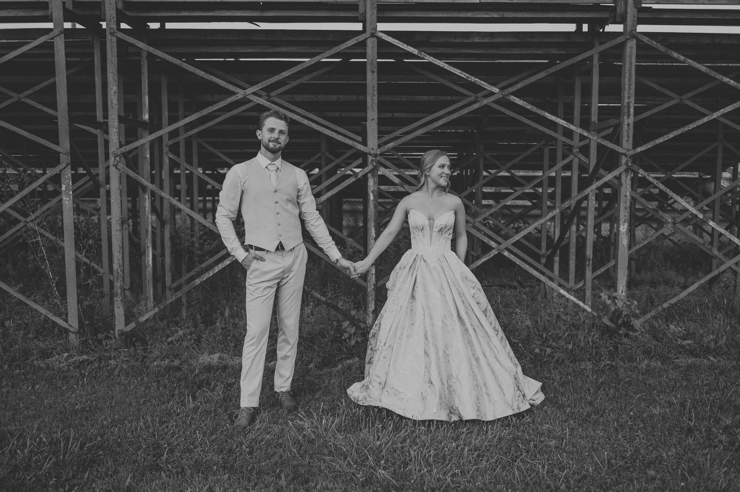 Black and white panoramic wedding photos taken against industrial scaffolding backdrop.