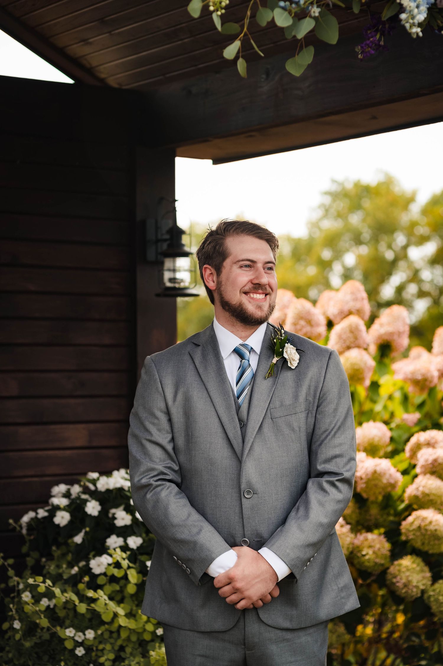 Beautiful pink hydrangeas bloom beside dark wooden structure in garden setting.