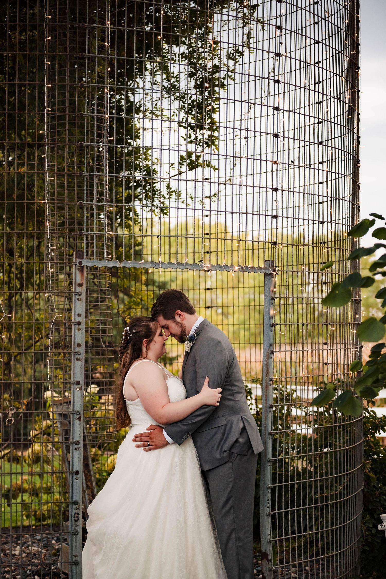 A romantic moment captured against an industrial metal fence backdrop.